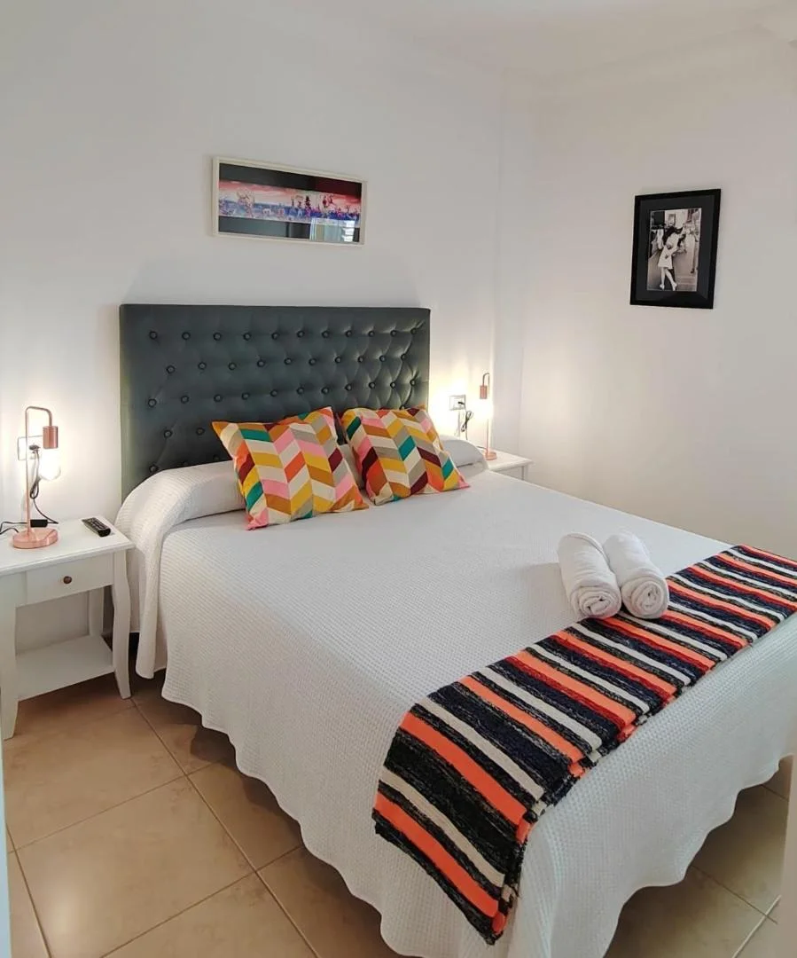 Dormitorio con cabecero gris y cojines de colores